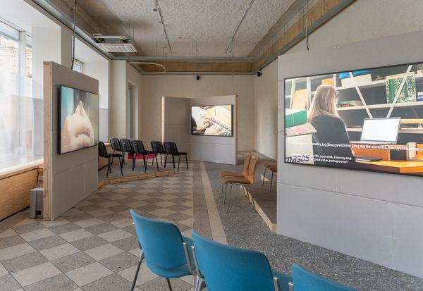 undefined, Metrica No. 5, 2026, 2026, Three-channel video installation with 5-channel audio, 20m TRT, Shot and performed on location in 2025, the artwork follows three psychotherapists as they enter the storage rooms of the Martynas Mažvydas National Library of Lithuania. Surrounded by shelves of documents, the women at the center of the performance score listen, question, and respond as the archive attempts to describe its fears and desires. Critical questions of selfhood, consciousness, and collective experience form and unravel as the sessions reflect upon the procedures of psychotherapy as they might apply to a subject whose “mind” is composed of an unfathomable mass of undead human writing. 

This new work is also part of Metrica, an evolving series of performances that stage encounters between public archives, psychoanalysts, and artificial intelligence, initiated by the artist duo in 2023 during their first stay in Vilnius at the Rupert residency programme. Their initial interest in land ownership histories in the region led Benedict and Rueter to two distinct repositories within Lithuanian history: the books of the Lithuanian Metrika—foundational administrative records of the 13th–17th century Duchy of Lithuania, held in 200 codices that have all been removed from Lithuania (the existing volumes are now in Moscow)—which have been digitized in a limited way by historians at Vilnius University; and oral histories of the 1990s post-Soviet Lithuanian administrative processes, developed by the newly independent state to re-privatize and repatriate land, which eventually resulted in a new digital government land register. Out of encounters between these archives, the artists, and artificial intelligence systems, the Metrica series produces a variety of conversational forms that engage what might be understood as the institutional unconscious.

For the most recent performances (Metrica No. 5-7, 2025 – ongoing), Benedict and Rueter invite professional psychotherapists to conduct intake sessions with the “psyches” of public archives. Voiced through an AI agent engineered by the artists, the archival psyches draw from historical land records, administrative documents, and literary texts – official records recast as personal memories. 
